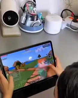 A child’s hands playing Minecraft on a tablet